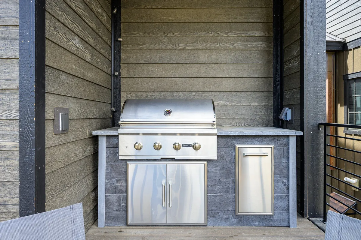 An inviting outdoor grilling station with a stainless steel grill, countertop, and storage cabinets, perfect for summer barbecues and alfresco dining. The setup suggests warm-weather gatherings, socializing, and making the most of sunny days.