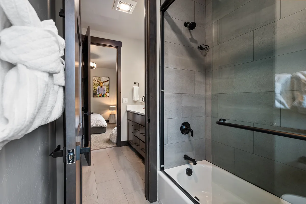 A spa-inspired bathroom with a modern bathtub, glass shower, elegant vanity, and a plush robe hanging nearby. The space feels serene, inviting, and designed for self-care routines, echoing the look and feel of a luxury spa.