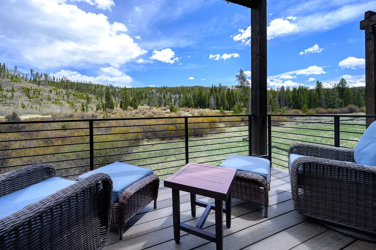 A tranquil outdoor seating area with wicker chairs and a small wooden table, set against an expansive view of nature. The peaceful scene highlights changing landscapes and a sense of seclusion—perfect for wildlife watching, enjoying river views, or unwinding in any season.