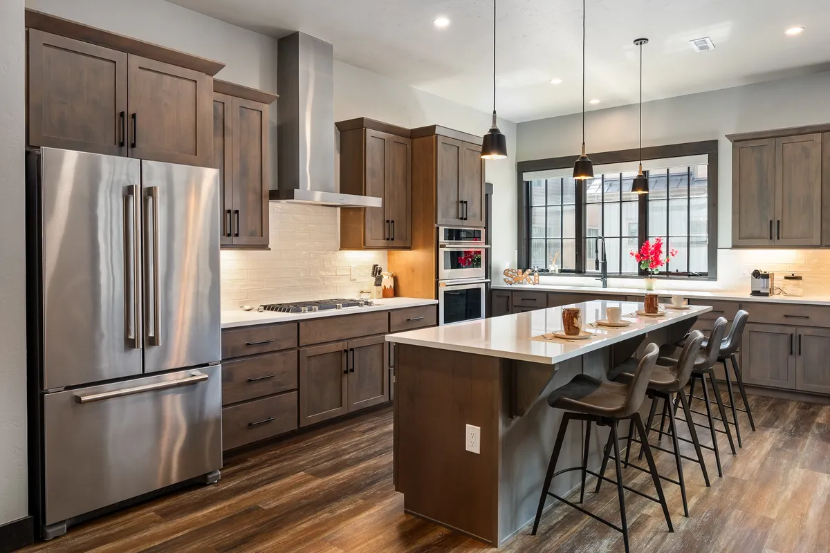 A modern gourmet kitchen with an expansive granite island, stainless steel appliances, and large windows letting in natural light. The space is designed for both cooking and gathering, with modern cabinetry and a welcoming, open feel.