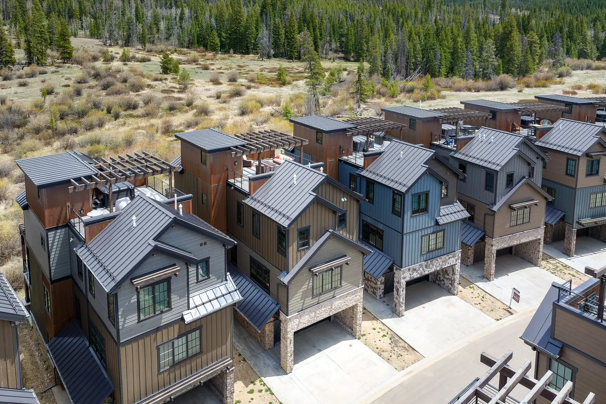 This image features a row of modern townhouses nestled among pine trees, with a landscaped area in the foreground. The scene exudes a welcoming and serene atmosphere, suggesting easy access to outdoor activities and neighborhood exploration.